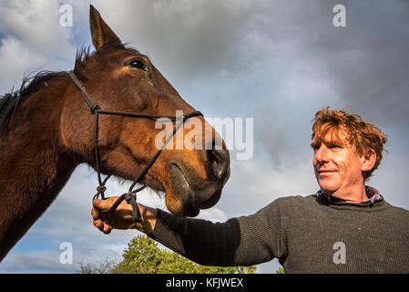 Close up portrait of smiling man / holding propriétaire de chevaux warmblood brun à l'extérieur Banque D'Images
