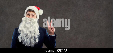 Le père Noël en costume d'affaires showing Thumbs up symbole de victoire Banque D'Images