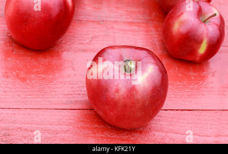 Pommes rouges bien mûrs se coucher sur une table de bois sur les feuilles d'érable colorées en jardin d'automne Banque D'Images