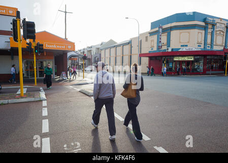 Un homme et une femmes utilisent le passage pour piétons à l'angle des rues d'Oxford et Vincent à Leederville, Perth, Australie occidentale. Banque D'Images