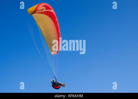 Dire bonjour et parapente voler dans un ciel bleu profond dans les alpes du sud. Banque D'Images