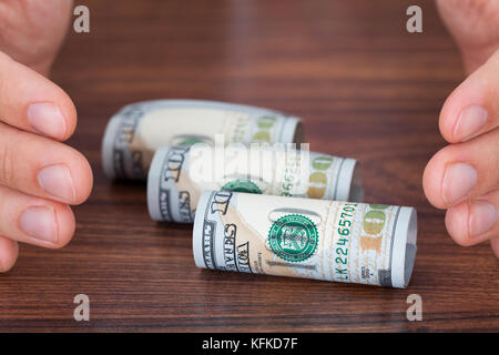 Portrait des mains la protection des billets de banque roulés sur la table Banque D'Images