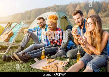 Les amis de manger une pizza au camping Banque D'Images