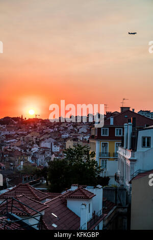 Vue sur les toits de Lisbonne dans le Bairro Alto, avec une grue encadrant le coucher du soleil et un avion s'envoler Banque D'Images