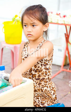 Un peu thai girl aide ses parents vendent l'eau et des rafraîchissements dans un temple à Bangkok, Thaïlande. Banque D'Images
