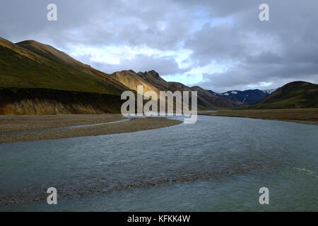 Coucher de soleil sur les montagnes de rhyolite, ciel nuageux et rivière qui coule à Landmannalaugar près du camping dans les Hautes terres centrales, réserve naturelle de Fjallabak, Islande Banque D'Images