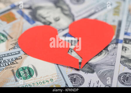 Gros plan de cœur rouge cassé sur les billets en dollars Banque D'Images