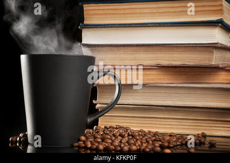 Grande tasse de café noir avec de la vapeur et de vieux livres sur le tableau noir. selective focus Banque D'Images