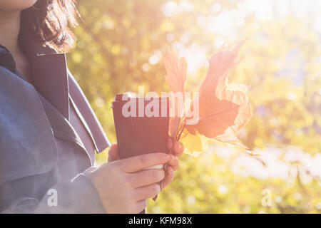Asian girl holding paper tasse de boisson chaude sur fond d'autumn park Banque D'Images