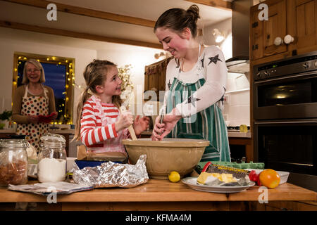 Deux soeurs sont la cuisson des gâteaux dans la cuisine avec leur grand-mère. Les filles sont le mélange des ingrédients. Banque D'Images