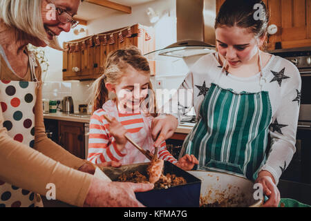 Deux soeurs sont la cuisson des gâteaux dans la cuisine avec leur grand-mère. Banque D'Images