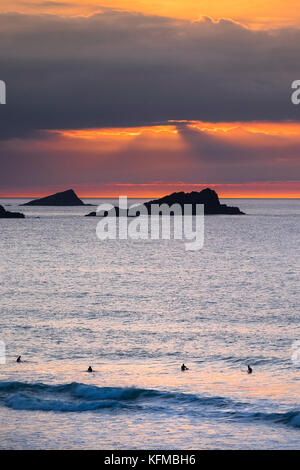 Coucher de soleil spectaculaire - la poule et le poussin de petites îles au large de pointe sont seeen Pentire en silhouette alors que le soleil se couche sur Cornwall dans Fistral. Banque D'Images