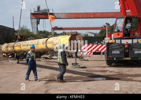 Tuyau offshore mis hors service levé par grue dans la cour de ferraille après livraison par camion des quais de Great Yarmouth. Banque D'Images