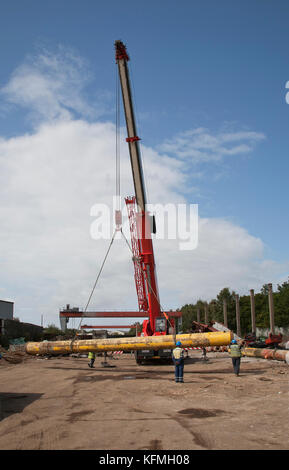 Tuyau offshore mis hors service levé par grue dans la cour de ferraille après livraison par camion des quais de Great Yarmouth. Banque D'Images