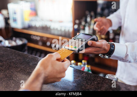 Le paiement du client à l'aide d'une carte de crédit. Carte de paiement étant effectué entre le client et le barman dans le café. Banque D'Images