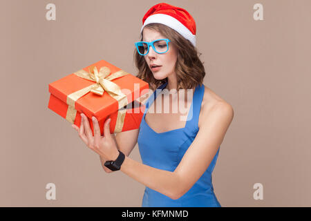 Cunning businesswoman looking at boîte-cadeau et que vous souhaitez ouvrir. trop fond brun. studio shot Banque D'Images