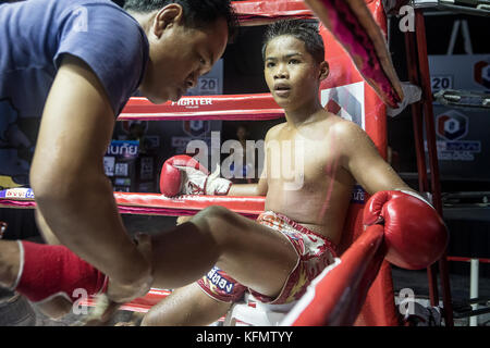 Jeune boxe thaï assis dans le conner du ring, assisté de ses cornermen, entre les rounds, Paktonchai, Korat, Thaïlande Banque D'Images