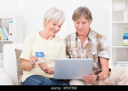 Happy senior couple shopping online à l'aide d'un ordinateur portable avec carte de crédit Banque D'Images