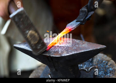 Forgeron forge manuellement le métal en fusion. blacksmith hammering hot metal blade. Banque D'Images