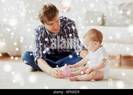 Heureux père avec bébé et tirelire à la maison Banque D'Images