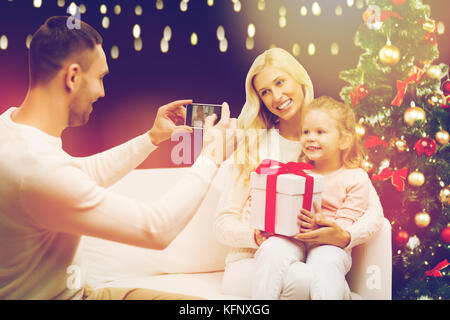 Man photographing son cadeau de Noël avec la famille Banque D'Images