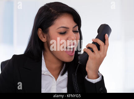 Portrait de femme en colère en criant sur téléphone Banque D'Images