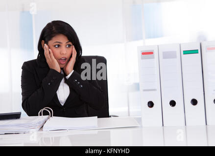 Choqué businesswoman looking at folder in office Banque D'Images