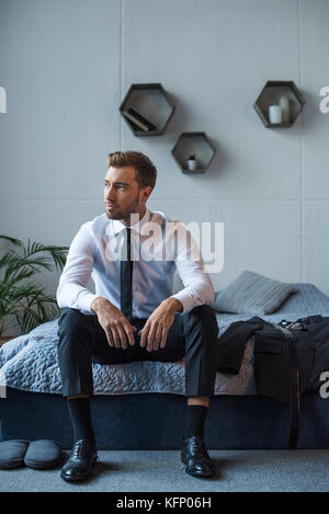 Businessman sitting on bed Banque D'Images