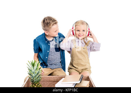 Les enfants avec des écouteurs, valise et ananas Banque D'Images