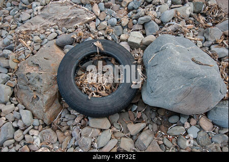 Caoutchouc d'un pneu de voiture est échoué sur une plage de galets sur l'île de Minorque en méditerranée Banque D'Images