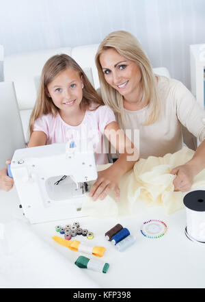 Portrait d'une belle jeune fille avec sa mère à coudre à la maison Banque D'Images