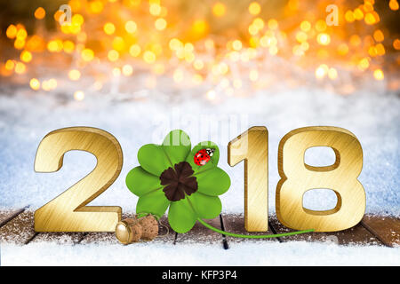 Happy new years eve silvester 2018 nombre d'or avec trèfle à quatre feuilles et coccinelle en face de l'arrière-plan flou lumineux sur la neige Banque D'Images