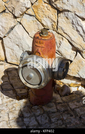 Un poteau incendie d'urgence situé en face d'un mur de pierre à Albufera au Portugal. Banque D'Images