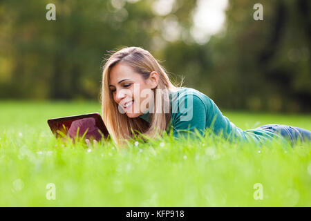 Jeune femme est using digital tablet in park Banque D'Images