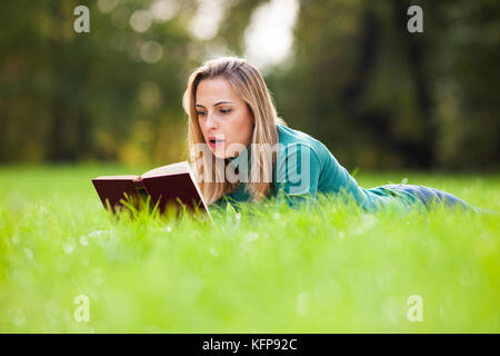 Jeune femme est en train de lire un livre dans le parc Banque D'Images