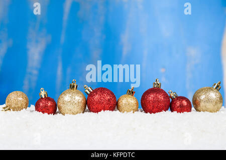 Le rouge et or boules de Noël sur la neige sur fond bleu. carte de vœux pour le nouvel an ou Noël, vue du dessus Banque D'Images