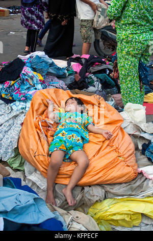 Une jeune fille est épuisé dormir sur une pile de vêtements de seconde main à orussei marché dans Phnom Penh, Cambodge. Banque D'Images