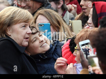 Wittenberg, Allemagne. 31 octobre 2017. La chancelière allemande Angela Merkel (CDU) fait prendre sa photo par des membres du public, après un service religieux marquant le 500e anniversaire du début de la réforme, devant la Schlosskirche (église du château) à Wittenberg, Allemagne, le 31 octobre 2017. Crédit : dpa Picture alliance/Alamy Live News Banque D'Images