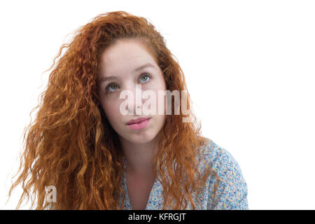 Belle femme est à la curiosité.. en pensant à l'avenir. une adolescente rousse a les cheveux bouclés et porte un costume blanc à fleurs. zone Banque D'Images