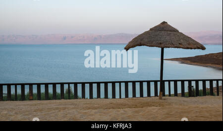 Tôt le matin, la lumière à l'Holiday Inn Resort Dead Sea, pas de personnes sur la plage et vue sur la mer, avec de la paille parasol, Jordanie, Moyen-Orient Banque D'Images