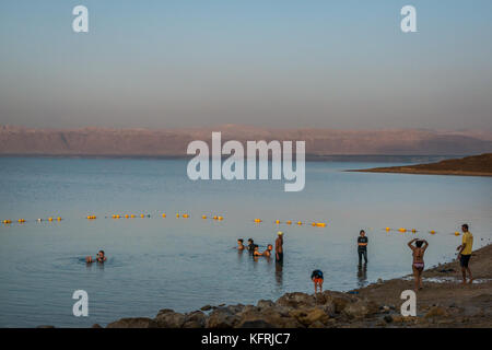 Tôt le matin, l'établissement Holiday Inn Dead Sea beach resort, la Jordanie avec des gens couverts de boue et flottant dans l'eau salée, et vue sur mer morte à Cisjordanie Banque D'Images
