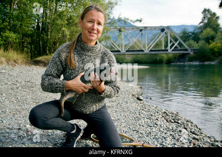 Caucasian woman est titulaire d'un saumon dans la rivière Squamish en Colombie-Britannique Banque D'Images