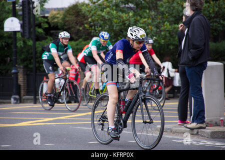 Femme moyenne dans un casque blanc chevauchant un vélo noir sur la course annuelle de cycle prudentiel de Londres. Londres, Royaume-Uni, été 2017. Banque D'Images