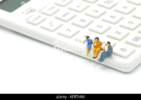3 miniatures des gens assis sur l'utilisation de calculatrice blanc comme arrière-plan concept d'entreprise avec l'exemplaire de l'espace. Banque D'Images