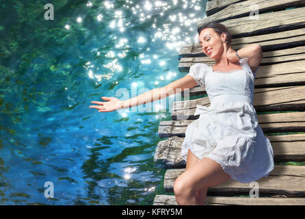 Vue de dessus de happy young woman lying on wooden path, contre l'eau claire. d'arrière-plan, le parc national des lacs de Plitvice, Croatie. concept environnemental Banque D'Images