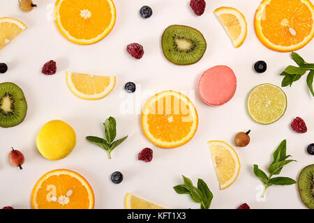 Mise à plat de la vie toujours avec ses macarons, fruits rouges, menthe et agrumes et autres fruits : fruits orange ; chaux ; Citron, kiwi sur fond blanc. Toujours tendance pop art Banque D'Images