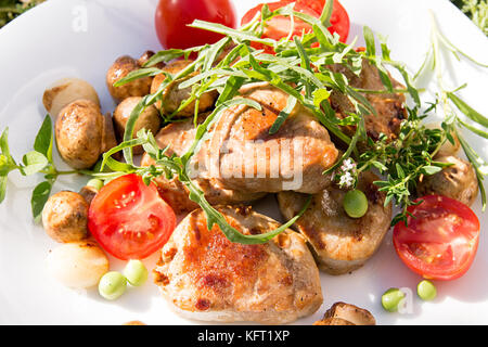 Médaillons de porc rôti avec des champignons, tomates et roquette on white plate Banque D'Images