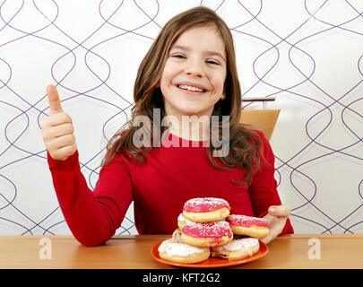 Happy little girl avec des beignets sucrés et thumb up Banque D'Images