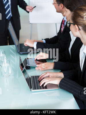 Image portrait d'une rangée d'entrepreneurs travaillant sur des ordinateurs portables et tablettes au cours d'une présentation ou d'une réunion Banque D'Images
