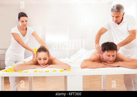 Masseurs professionnels dans un bain à donner en retour à un joli massage mari et femme baignant côte à côte Banque D'Images